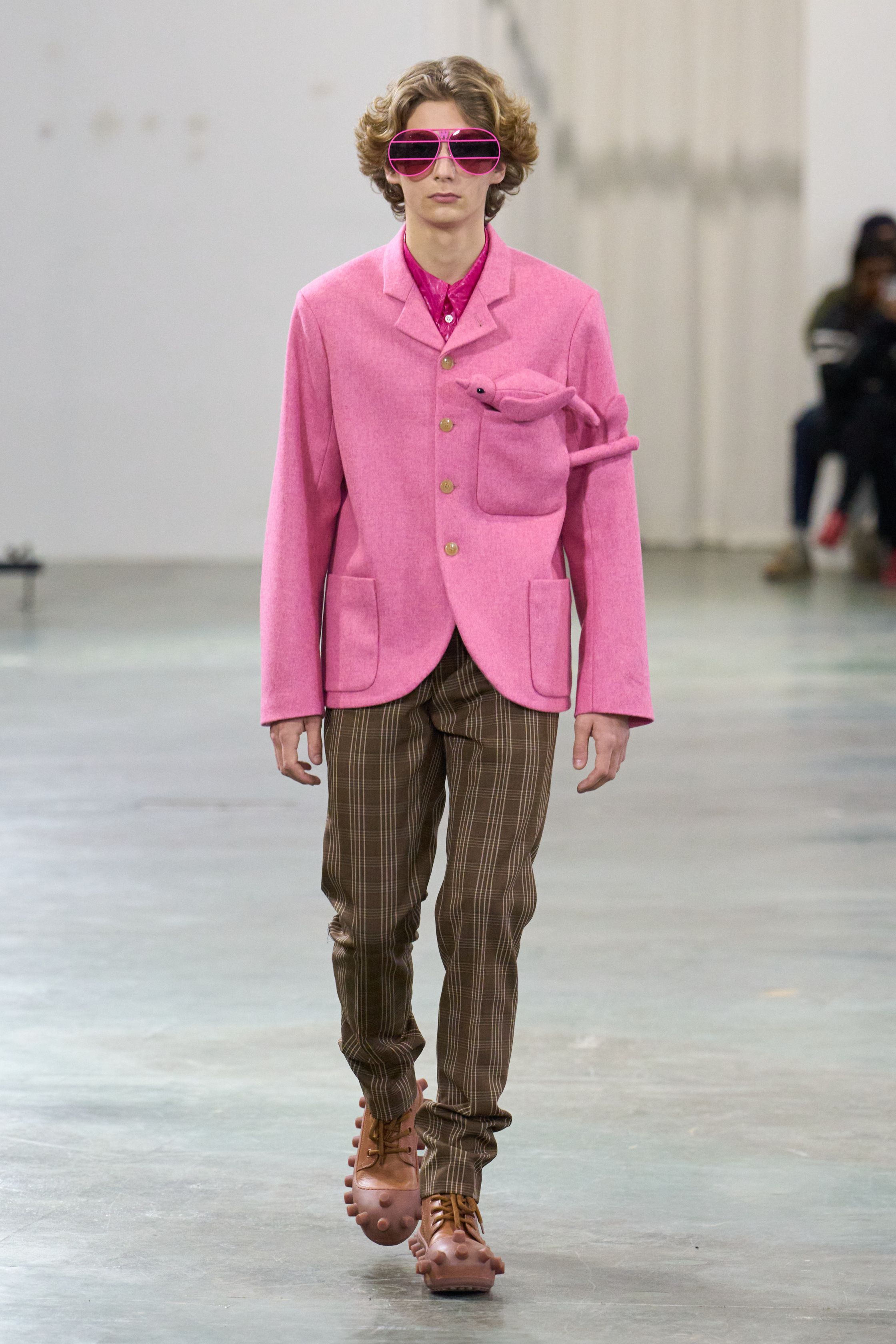 Walter Van Beirendonck 2026秋冬以高度饱和的色彩、夸张比例与童真符号继续挑战男性气质的既定边界。针织花朵、卡通图案、结构化西装与机能裤装并置，构建出介于游戏、政治隐喻与乌托邦幻想之间的舞台。系列拒绝低调，刻意制造视觉噪音，用快乐、怪诞与不合时宜的色彩作为对现实焦虑的反击，呈现一场毫不妥协的时装宣言-顽石频道趋势研究